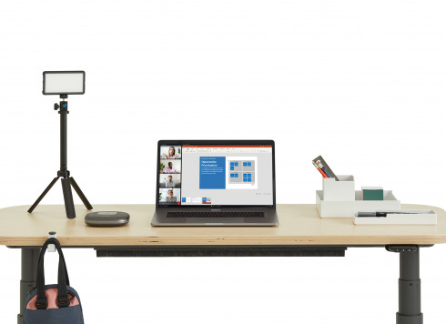 Home Office Work Station equipped with a Height-Adjustable Desk, a laptop, Lumecube Broadcast Lighting Kit​, Anker PowerConf Bluetooth Speakerphone​, white SOTO Bundle with office supplies.